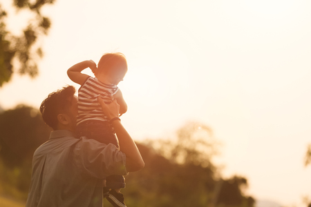 Daddy carrying son on his back at the sunset.の写真素材