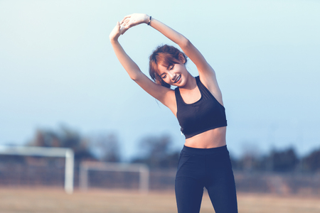 Female runner doing stretching exercise, preparing for morning workout in the park.の写真素材