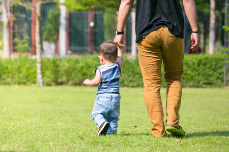Joyful father hold hand his son walking at home.の写真素材