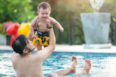 Playful father and son having fun in water.の写真素材