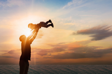 Father throwing his son on the beach at the sunset time. Concept of friendly family.の写真素材