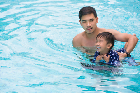 Playful father and son having fun in water.の写真素材