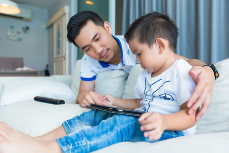 Father and his son playing with tablet computer at home.の写真素材
