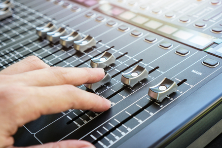 Hand adjusting audio mixer console buttons, faders and sliders.の写真素材