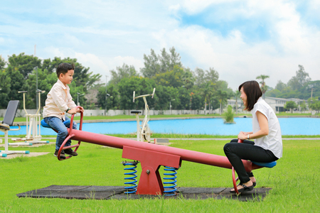 Mother with son playing seesaw in the park.の写真素材