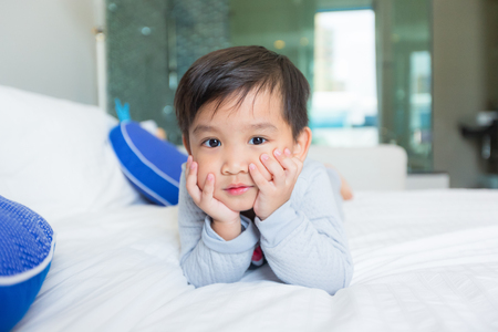 Little boy in pajamas lying in bed in the morning.の写真素材