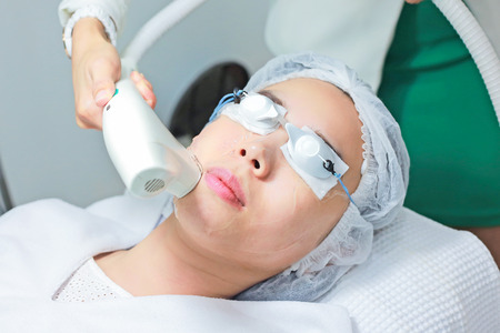 Close-up of Beautician Giving Laser Epilation Treatment To Young Woman Face.の写真素材