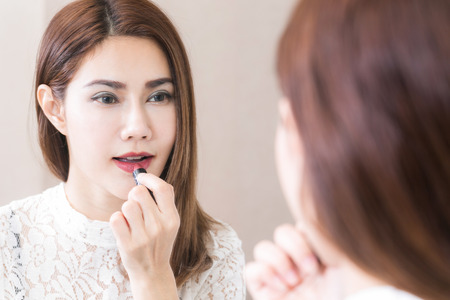 Portrait in mirror of smiling caucasian young woman model with glamour red lips and bright makeup.の写真素材