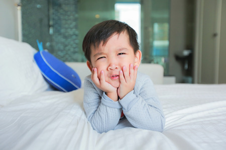 Little boy in pajamas lying in bed in the morning.の写真素材