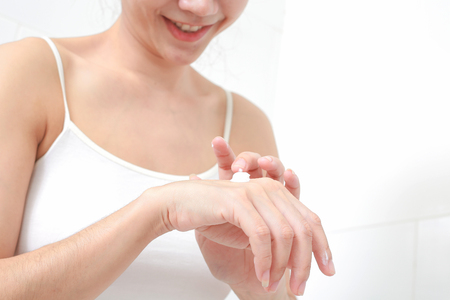 Young woman applies cream on her hands.の写真素材