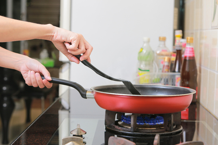 Woman holding a pan in the hand cooking omelette in kitchen.の写真素材