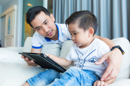 Father and his son playing with tablet computer at home.の写真素材