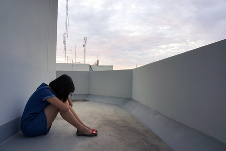 Sad and lonely woman in the city sitting side balcony.の写真素材