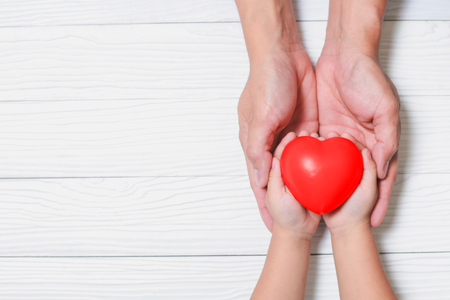 Father Day's and Mother's Day. Man holds his hands son supporting red heart.の写真素材
