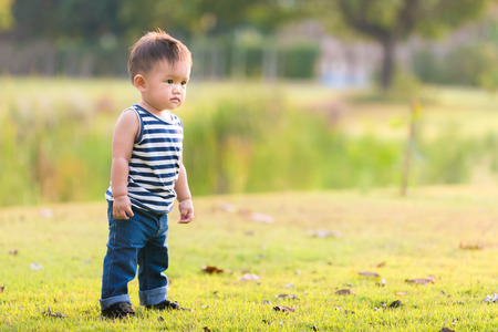 Happy baby boy standing in grass on the fields. Smiling child outdoorsの写真素材