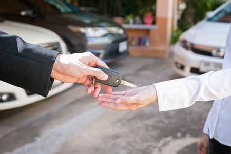 Salesman offering car key to a customers at showroom used car.の写真素材