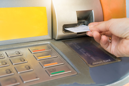 Hand inserting ATM card into bank machine.の写真素材