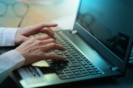 Side view of female hands typing on laptop keyboard.の写真素材