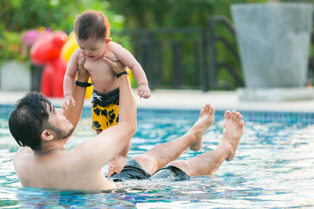 Father and son funny in water pool summer day. Leisure and swimming at holidays.の写真素材