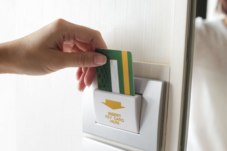 Female hand insert room card key to open electric light hotel room.の写真素材