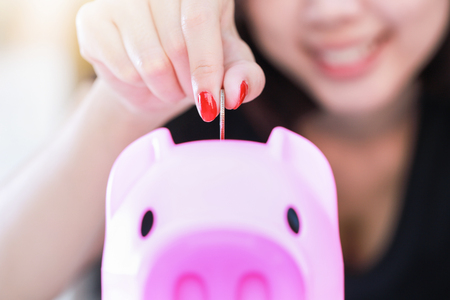 Female hand putting money into piggy bank.の写真素材