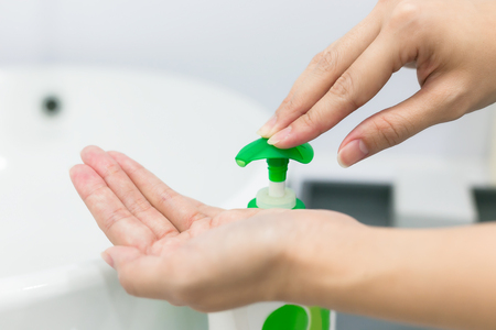 Female hands using wash hand sanitizer gel pump dispenser.の写真素材