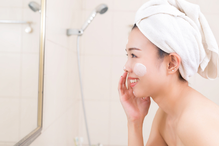 Close-up of beautiful young woman applying cream with bath towel.の写真素材