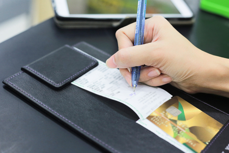 Consumer hand signing on a sale transaction receipt with credit card.の写真素材