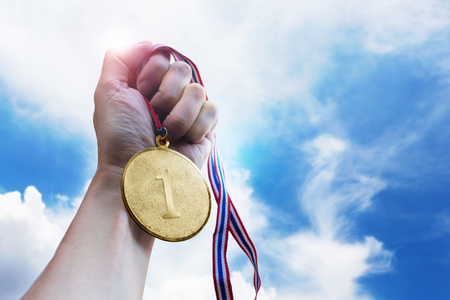 Businessman hand holding golden coin medal on the sky.の写真素材