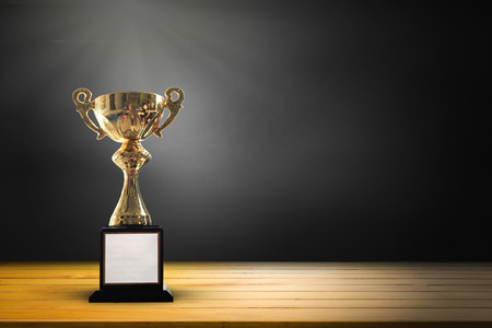 Champion golden trophy on wooden table background. Copy space for text.の写真素材
