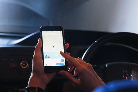 Close-up woman using map application on smartphone at night.の写真素材