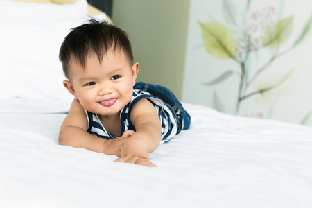 Adorable baby boy smiling on bedroom.の写真素材
