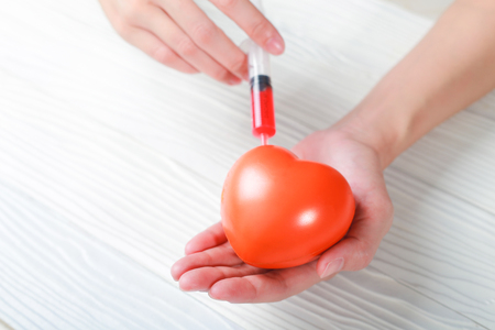 Hand holding plastic with Syringe fill in heart.の写真素材