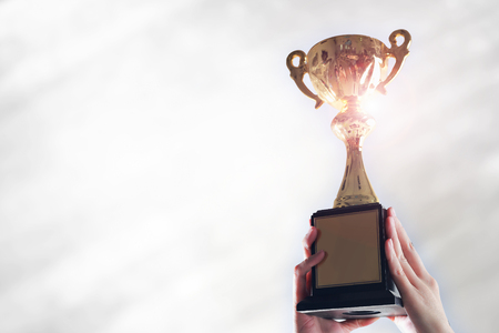 Business hands holding trophy cup on white background.の写真素材