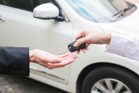Salesman offering car key to a businessman from the car dealer.の写真素材