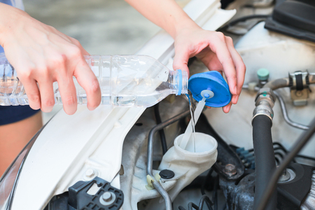 Hands of filling water into the canister of the car windscreen wiper system.の写真素材