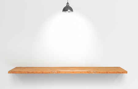 Wooden shelf with lamp on white wall.の写真素材