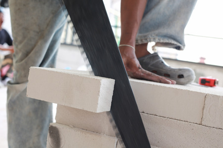 Worker cutting bricks with crosscut saw.の写真素材