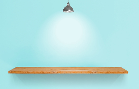 Wooden shelf with lamp on blue vintage wall.の写真素材