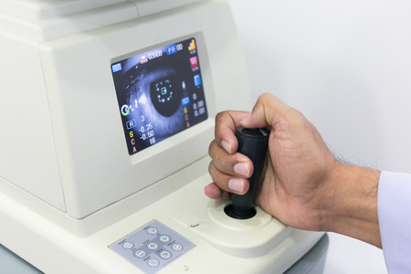 Close-up of hand optometrist adjusting phoropter for patient. Eye sight and healthcareの写真素材