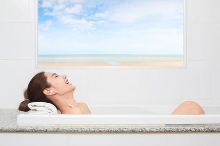 Just relax. Content beautiful young woman relaxing while taking a bath.の写真素材