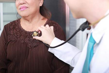 Doctor using stethoscope to exam woman patient heart.の写真素材