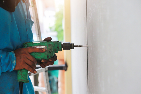 A drilling machine is making hole on wall of tiles.の写真素材