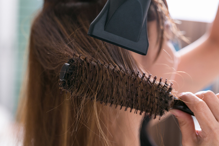 Drying blond hair with hair dryer and round brush.の写真素材