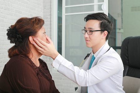 optometry concept - pretty young woman having her eyes examined by an eye doctorの写真素材