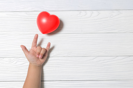 Baby loved hands giving red heart on white wood background.の写真素材