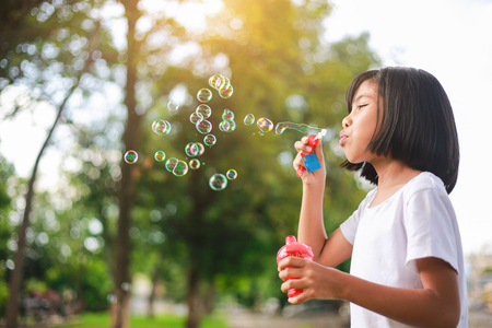Little Asian girl blowing bubbles in the garden.の写真素材