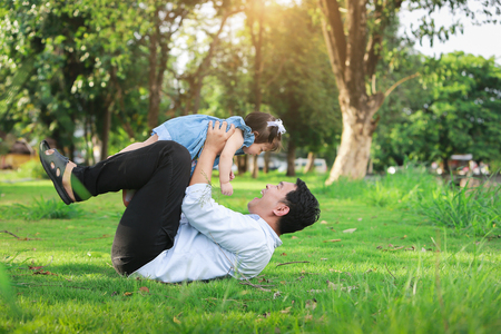 Father and little girl play lying on grass, low angleの写真素材
