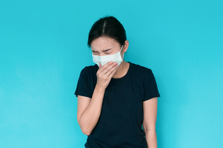 Young woman having headache on blue background.の写真素材