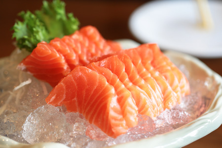 Salmon raw sashimi on ice Japanese traditional dish on wooden table.の写真素材